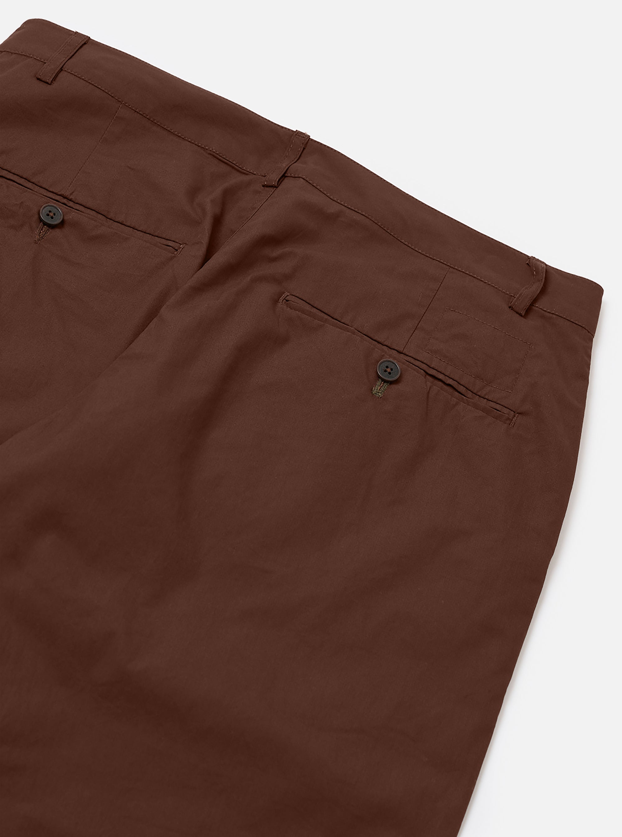 The Brown Peached Poplin Military Chino is shown from the back as a flat lay against a plain white background. The image highlights the two rear jetted buttoned pockets and the straight-cut design of the legs. The smooth, brushed texture of the brown cotton poplin fabric is visible.