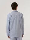 A model wears the Navy Kennedy Stripe Three Button Jacket over a light-colored top against a plain white background. The jacket features a vertical pinstripe pattern, three buttons, and front patch pockets. The image shows the model from the waist up, focusing on the fit and drape of the garment.