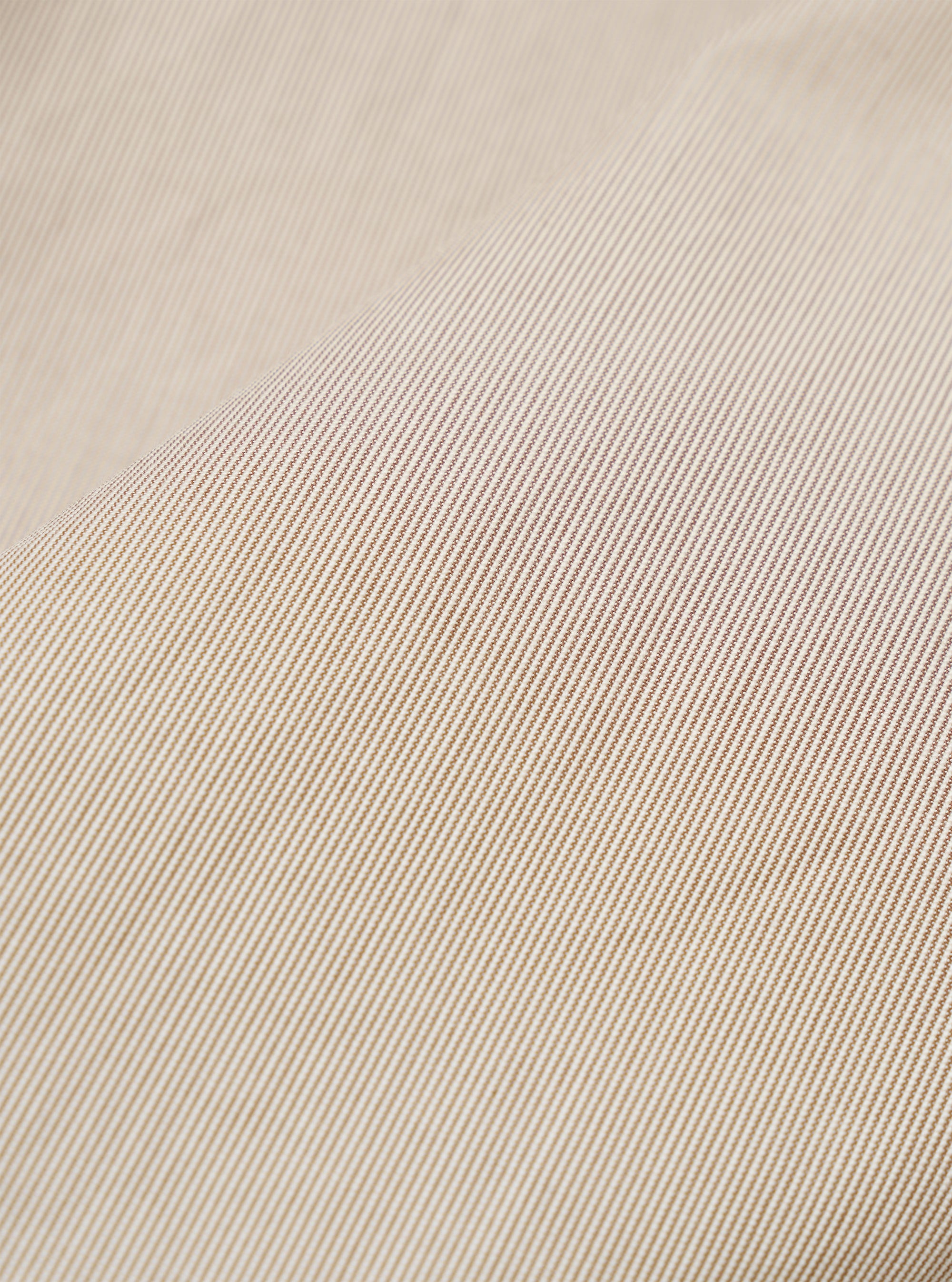 A close-up fabric swatch of the Brown Kennedy Stripe Three Button Jacket shows a detailed view of the brown cotton material with a thin, light-colored vertical stripe pattern. The fabric fills the frame, highlighting the fine texture and color of the suiting material.