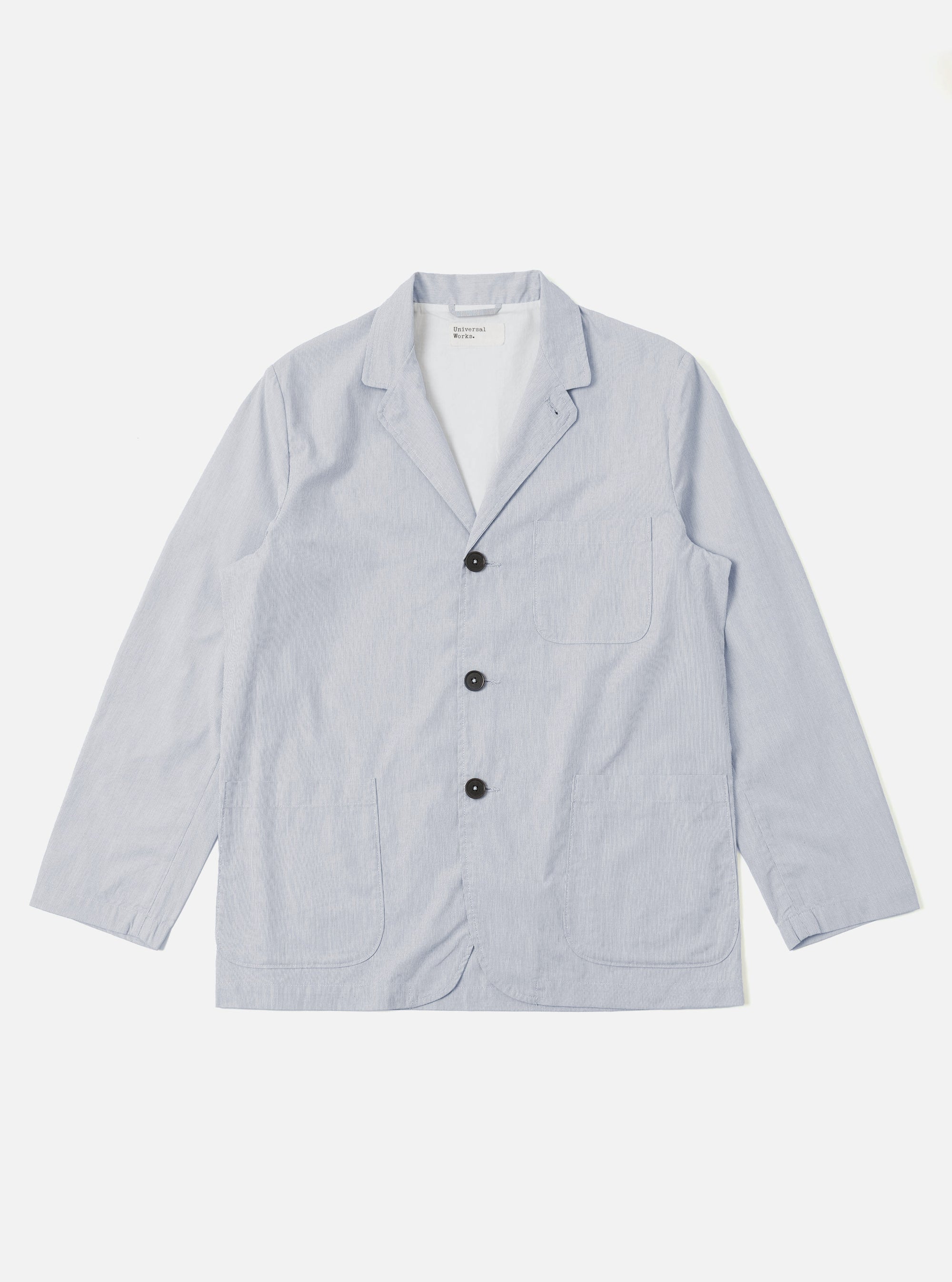 The Navy Kennedy Stripe Three Button Jacket is shown as a flat lay against a plain white background. The jacket features a three-button front closure, a notched lapel, and three front patch pockets, including one chest pocket and two larger pockets at the waist. The navy blue cotton fabric has a distinct vertical white stripe pattern.