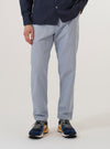 A model wears the Navy Kennedy Stripe Military Chino while standing against a plain white background. The image shows a front view of the trousers, highlighting the straight-leg fit and the vertical white pinstripe pattern on the navy blue cotton fabric. The trousers feature a button waist and a visible fly. The model is wearing the chinos with a light-colored top and dark shoes.
