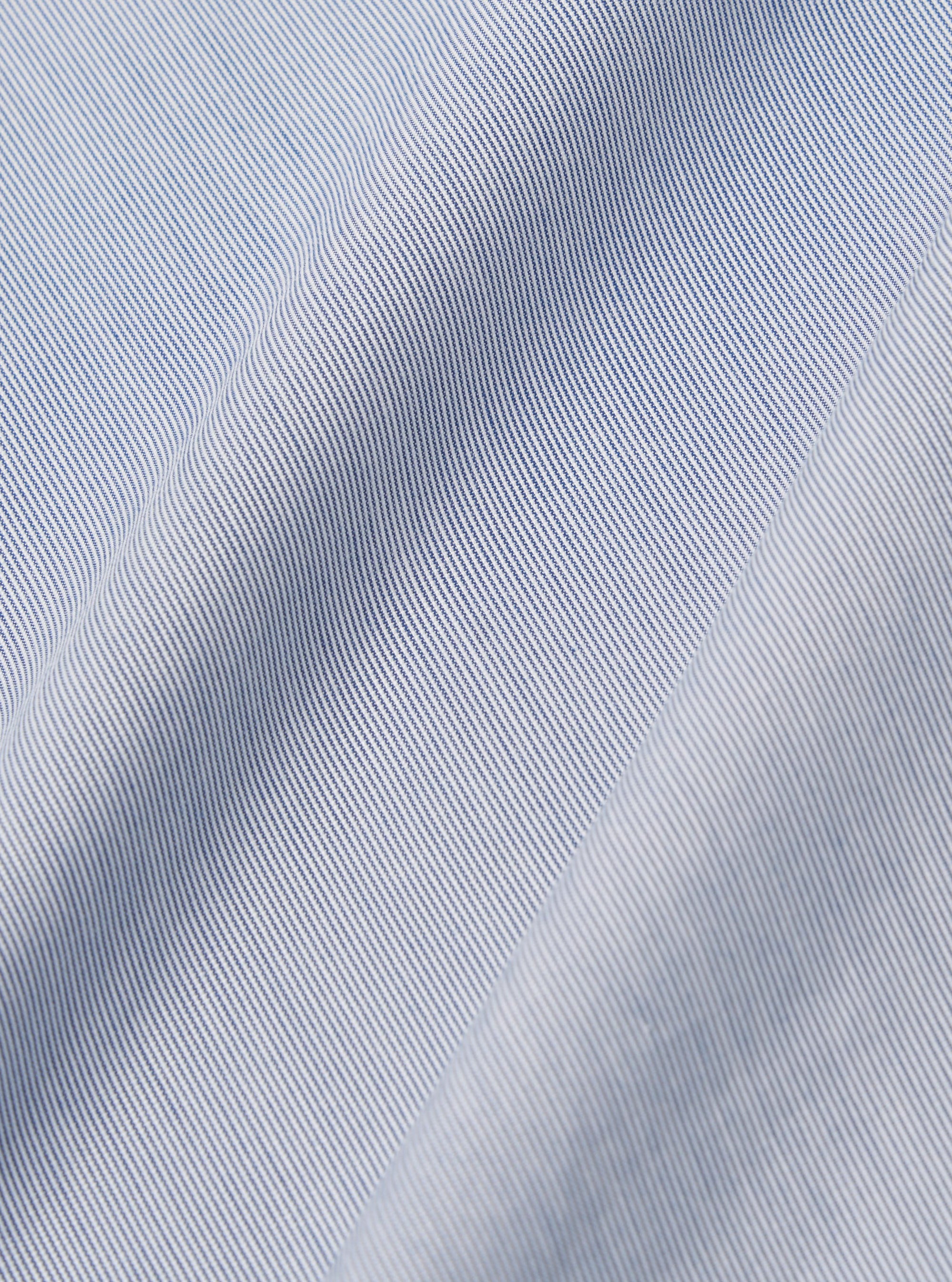 A close-up fabric swatch of the Navy Kennedy Stripe Military Chino displays a navy blue cotton material with distinct white vertical stripes. The image focuses on the fine texture of the weave and the pattern detail.