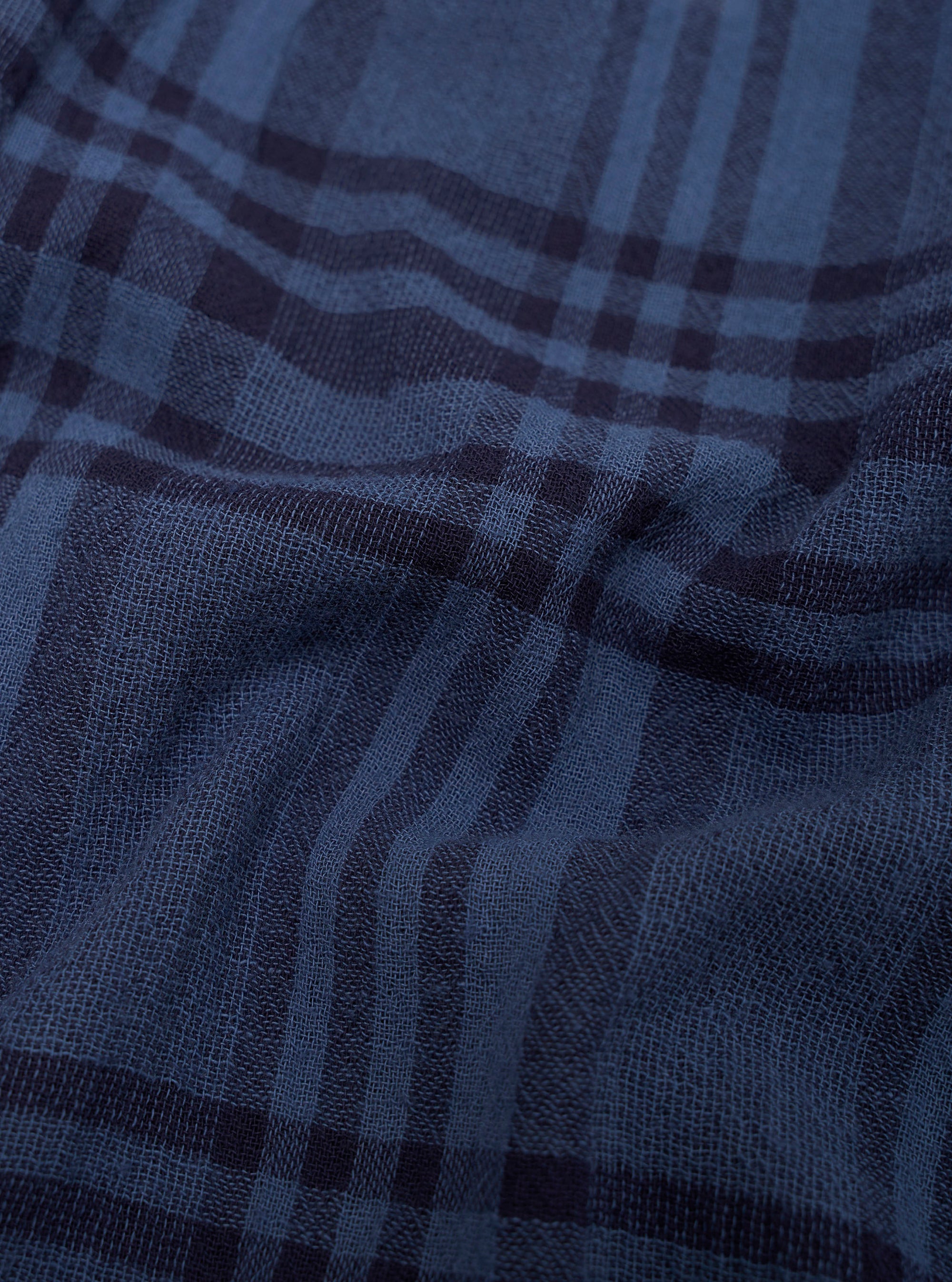 Close-up of blue plaid fabric with a focus on texture and pattern.