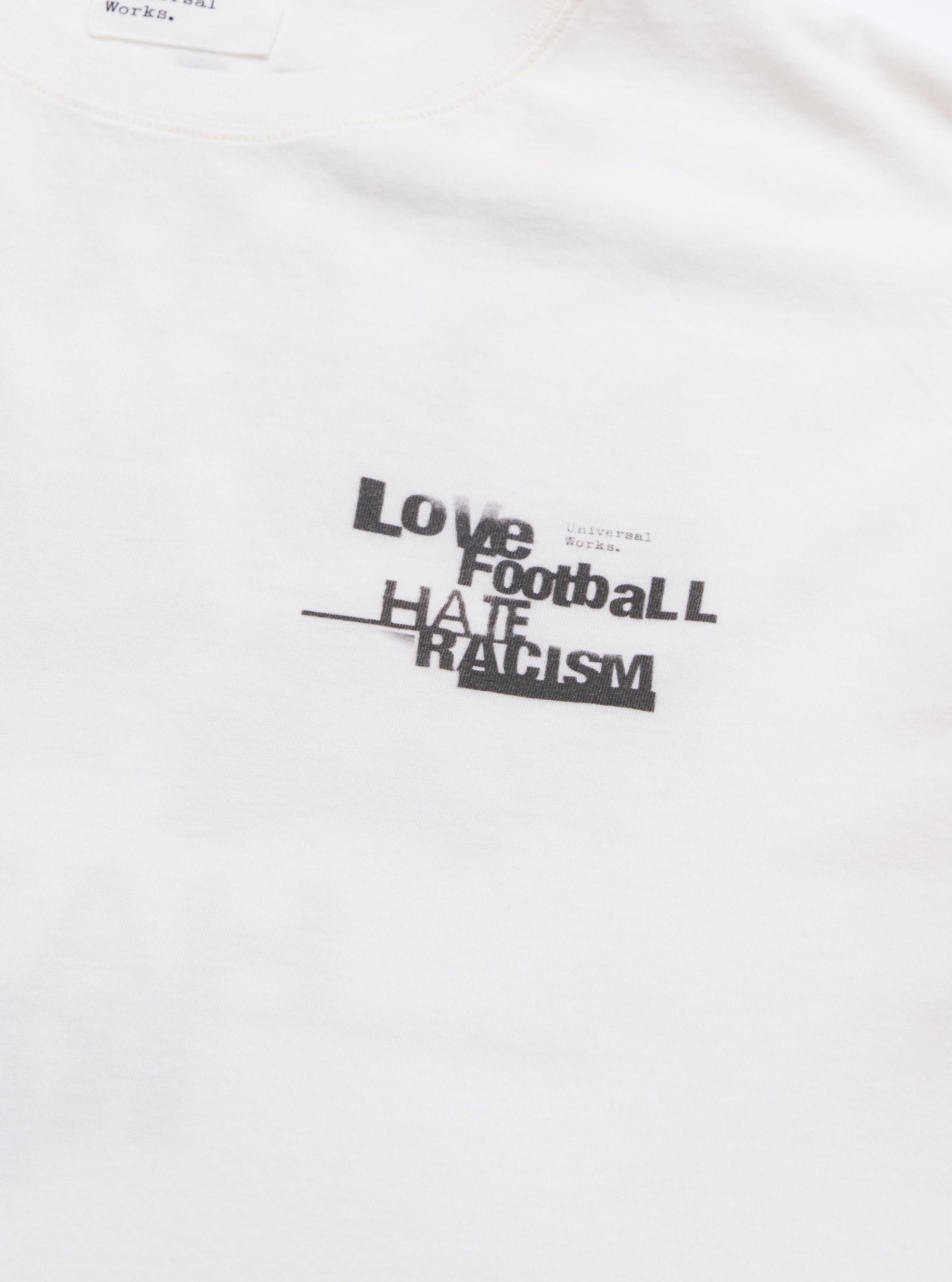 The Ecru Love Football Jersey Print Tee is shown from the back as a flat lay against a plain white background. The image highlights the clean construction of the garment's rear panel and the soft texture of the ecru cotton jersey fabric.