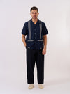 The Navy Classic Oxford Tropicana Shirt is displayed as a flat lay against a plain white background. The shirt features a one-piece open collar, a full-button front, and short sleeves. Two large patch pockets are positioned at the hip, and the hem includes side splits. The navy cotton fabric has a visible oxford weave.