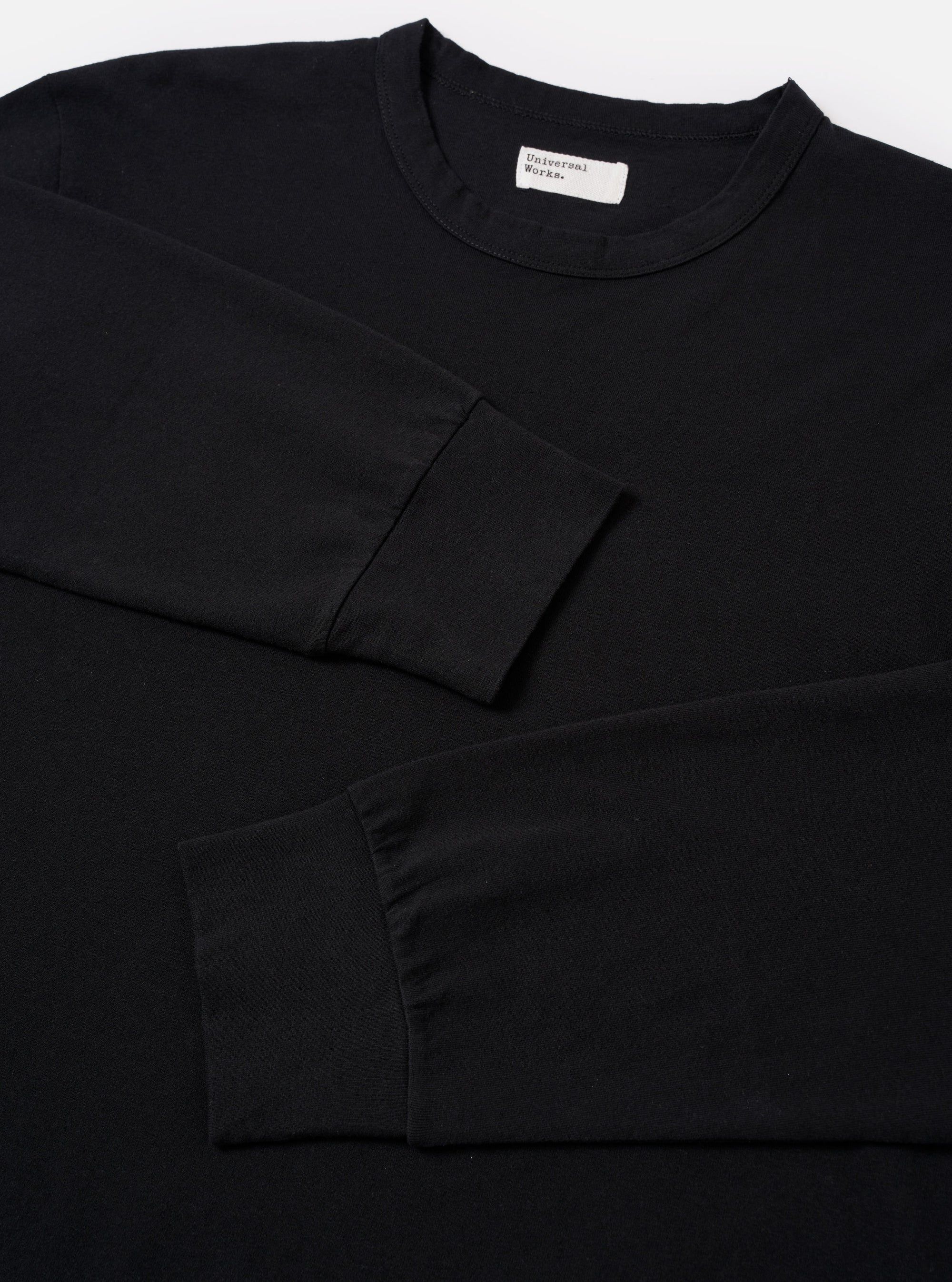 The Black Recycled/Bio Jersey Henry L/S Tee is shown from the back as a flat lay against a plain white background. The image highlights the clean construction of the long-sleeved t-shirt, featuring a straight hem and a simple crew neckline. The fabric is a solid black jersey.