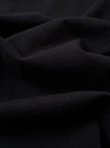 A close-up fabric swatch of the Black Recycled/Bio Jersey Henry L/S Tee displays the solid black color and the fine, soft knit texture of the recycled and organic cotton jersey material. The fabric fills the entire frame.