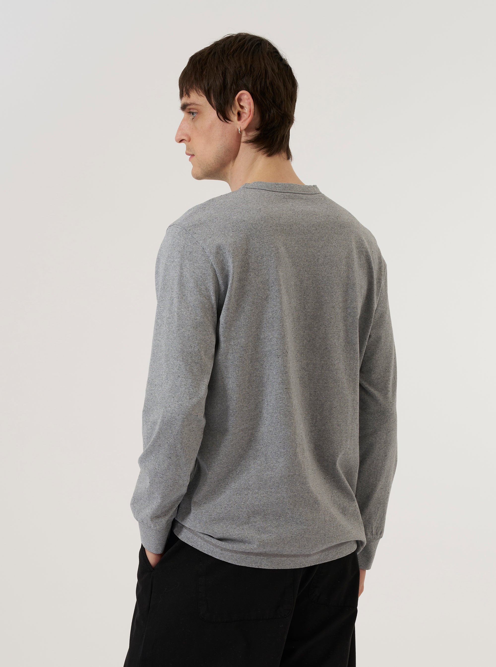 A model wears the Grey Marl Recycled/Bio Jersey Henry L/S Tee, shown from the back against a plain white background. The long-sleeved t-shirt is made from a soft, textured grey marl jersey fabric and features a relaxed fit, a simple crew neckline, and a straight hem.