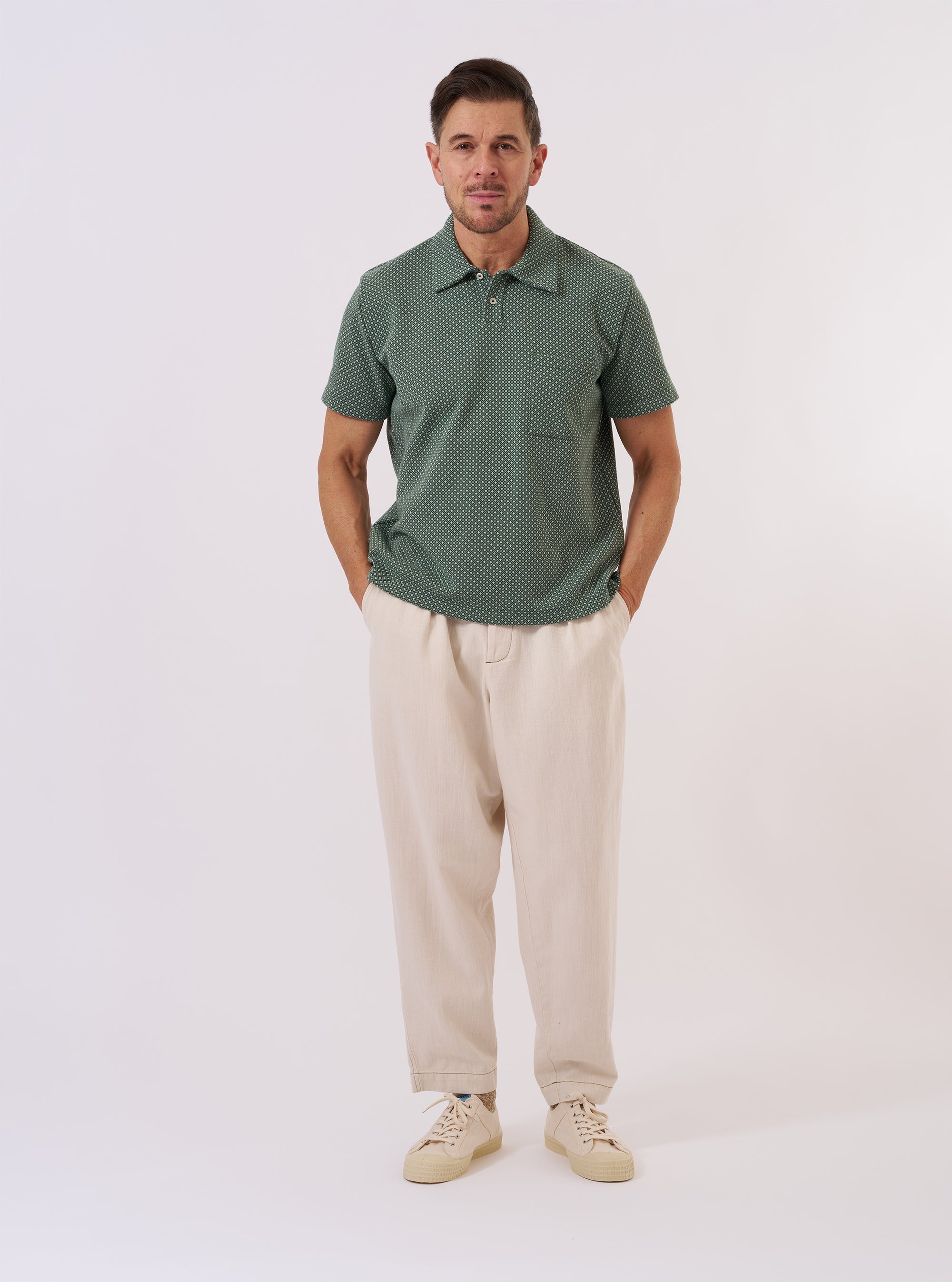 The Green Argyll Jersey Newlyn Polo is shown as a flat lay against a white background. The polo features a tonal green Argyll diamond pattern across the body, a classic collar, and a three-button placket.