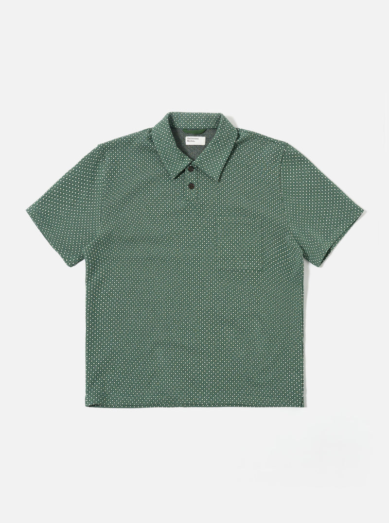 The Green Argyll Jersey Newlyn Polo is shown as a flat lay against a white background. The polo features a two-button placket, a one-piece collar, and a large patch pocket on the left chest. The fabric has a distinct green and white Argyll diamond pattern throughout.