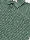 The Green Argyll Jersey Newlyn Polo is shown as a flat lay against a white background. The polo shirt features a green and white diamond argyll pattern throughout the fabric. It has a classic collar, a three-button placket, and short sleeves.