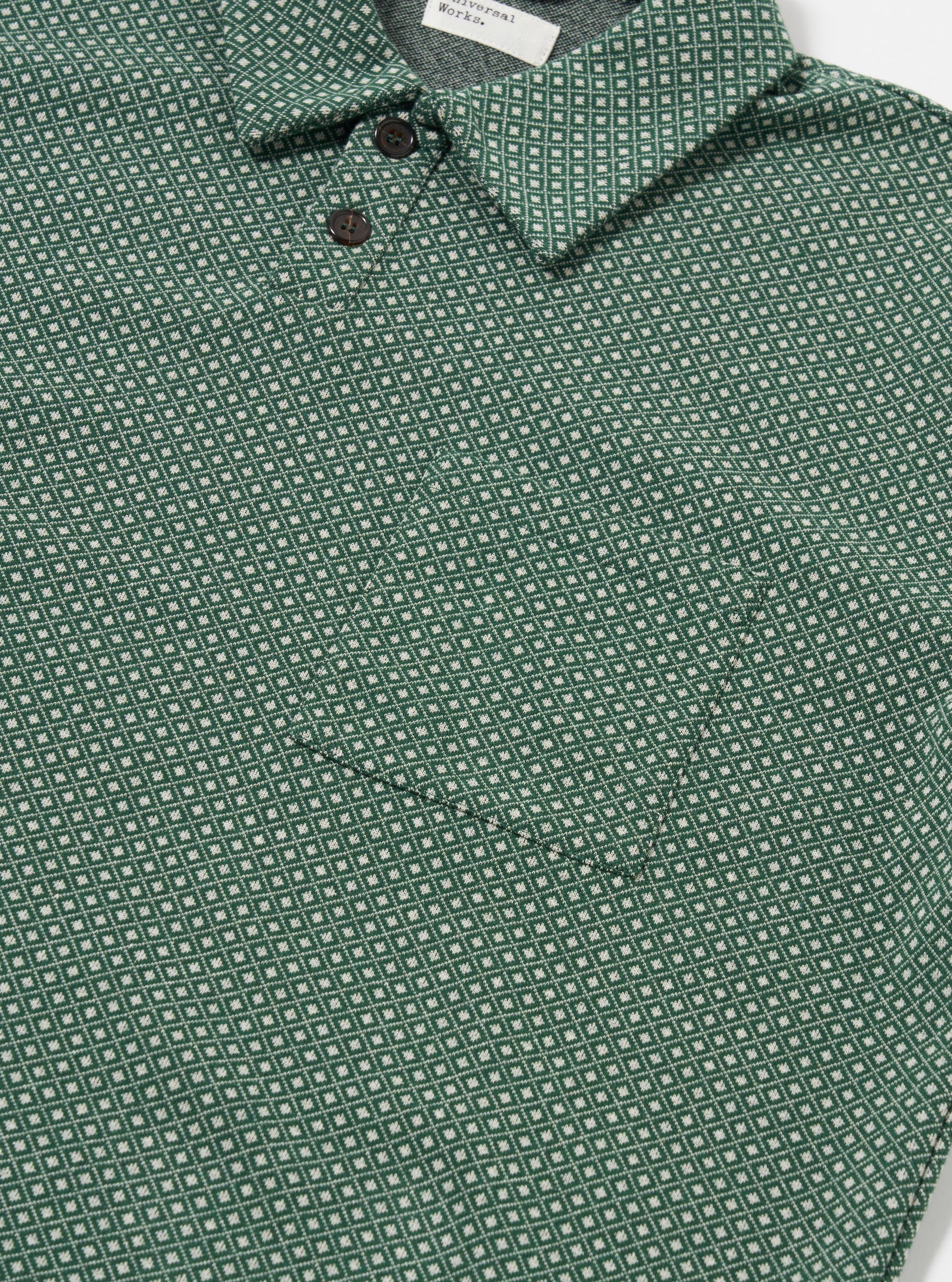 The Green Argyll Jersey Newlyn Polo is shown as a flat lay against a white background. The polo shirt features a green and white diamond argyll pattern throughout the fabric. It has a classic collar, a three-button placket, and short sleeves.