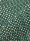 A close-up fabric swatch of the Green Argyll Jersey Newlyn Polo shows a green textile with a subtle, textured argyll pattern. The fabric is displayed flat, highlighting the intricate knit detail and varying shades of green.