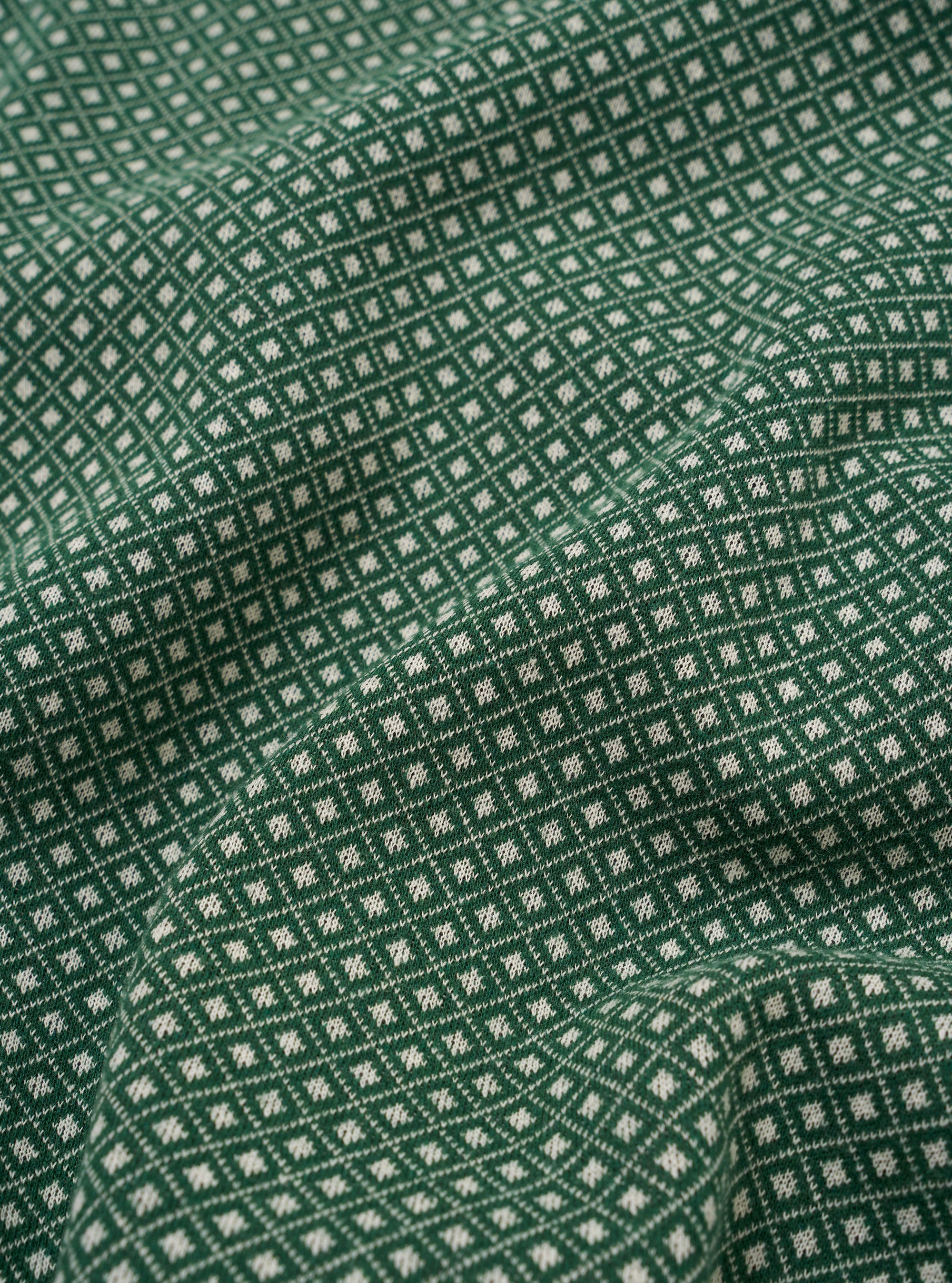 The Green Argyll Jersey Sleeveless Crew is shown from the back as a flat lay against a plain white background. The image highlights the garment's sleeveless design, ribbed crew neckline, and straight hem. The fabric features a prominent green argyll diamond pattern.