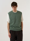 A model wears the Green Argyll Jersey Sleeveless Crew against a plain, light-colored background. The sleeveless sweater features a bold green and white argyle diamond pattern with a ribbed crew neck and ribbed armholes. The model is shown from the chest up, layering the knit vest over a white collared shirt.