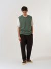 A model wears the Green Argyll Jersey Sleeveless Crew against a plain, light-colored background. The garment is a sleeveless sweater with a classic crew neck and a prominent green argyll diamond pattern across the front. The model is shown from the waist up, highlighting the fit and the texture of the knit jersey fabric.