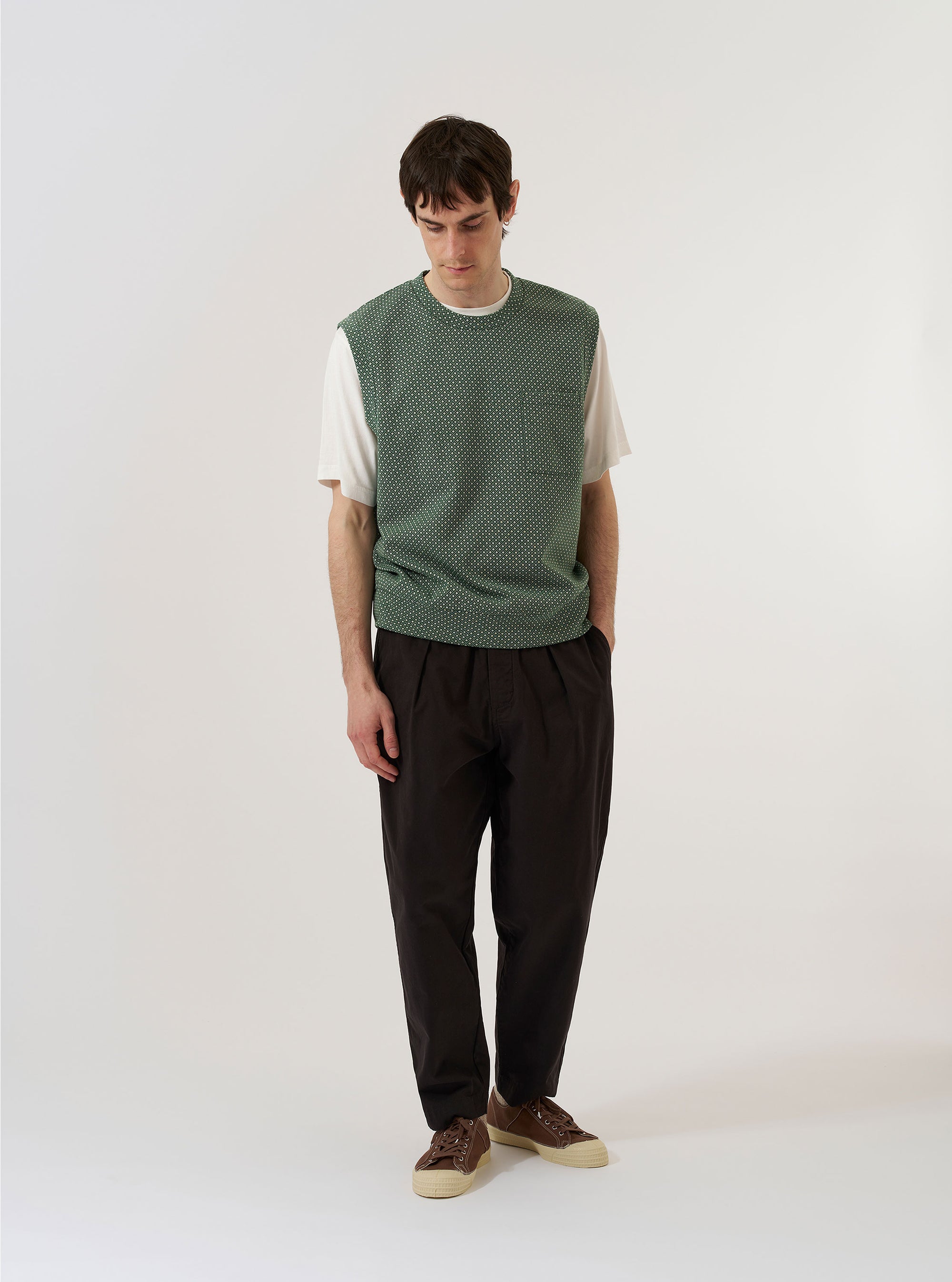 A model wears the Green Argyll Jersey Sleeveless Crew against a plain, light-colored background. The garment is a sleeveless sweater with a classic crew neck and a prominent green argyll diamond pattern across the front. The model is shown from the waist up, highlighting the fit and the texture of the knit jersey fabric.