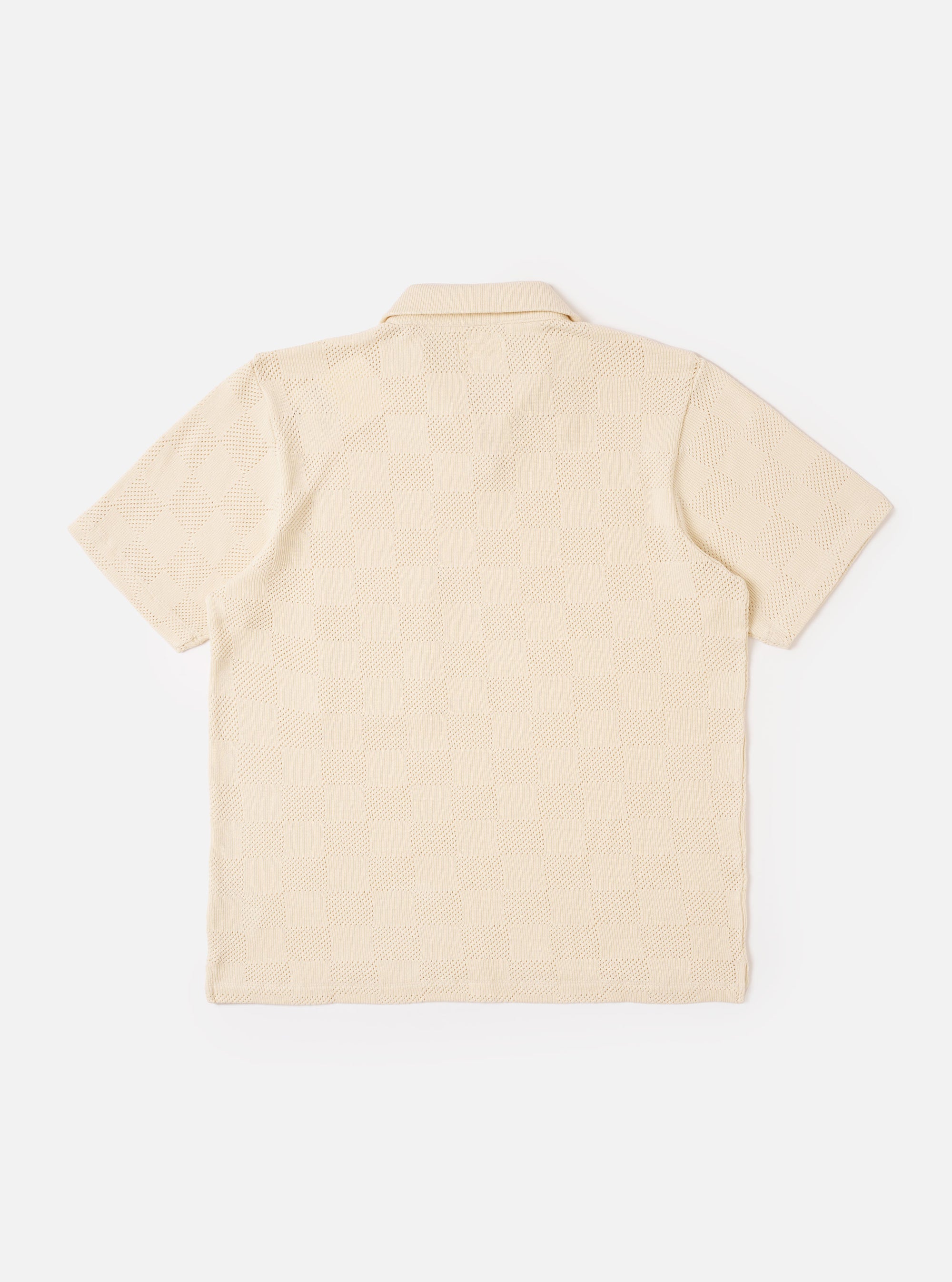 The Ecru Fantasy Checkerboard Vacation Polo is shown from the back as a flat lay against a plain white background. The polo features an all-over ecru and white checkerboard pattern, short sleeves, and a straight hem. The image highlights the clean construction and the textured organic cotton fabric.