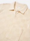 The Ecru Fantasy Checkerboard Vacation Polo is shown as a flat lay against a plain white background. The polo features a classic collar, a central button-down front, and short sleeves. The fabric is highlighted by an all-over textured checkerboard knit in a solid ecru color.