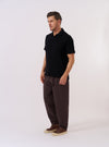 The Black Fantasy Checkerboard Vacation Polo is displayed as a flat lay against a plain white background. The polo features an all-over black and grey checkerboard pattern, a spread collar, and a short-sleeved design.