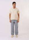 The Ecru Fantasy Checkerboard Vacation Polo is shown as a flat lay against a plain white background. The polo features a regular fit, a classic collar, a three-button placket, and a short-sleeved design with a split hem. The organic cotton fabric is decorated with an all-over fantasy checkerboard pattern in ecru and white.
