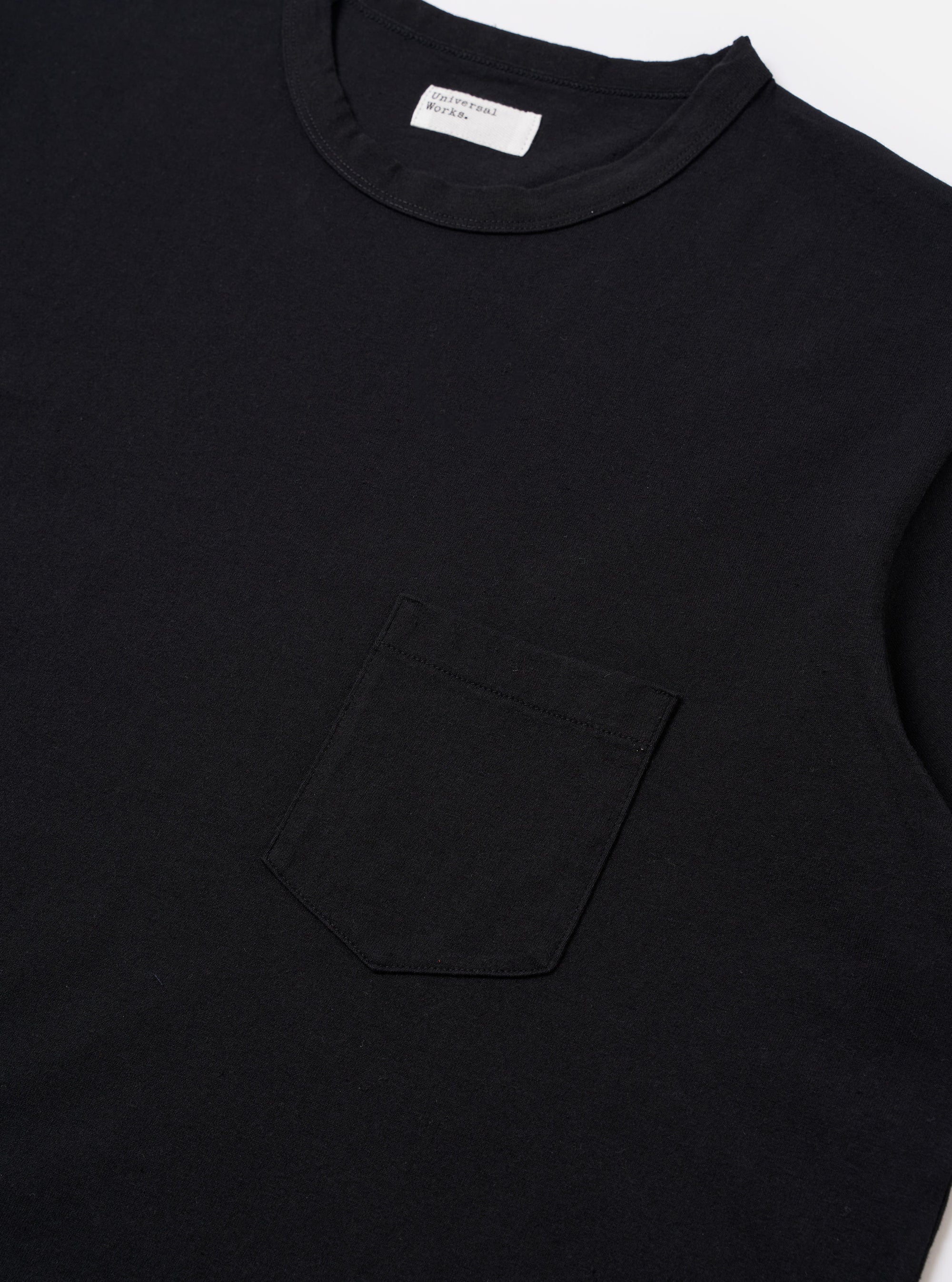 The Black Recycled/Bio Jersey Core Pocket Tee is shown from the back as a flat lay against a plain white background. The image highlights the clean, simple construction of the garment's rear and the smooth texture of the black jersey fabric.