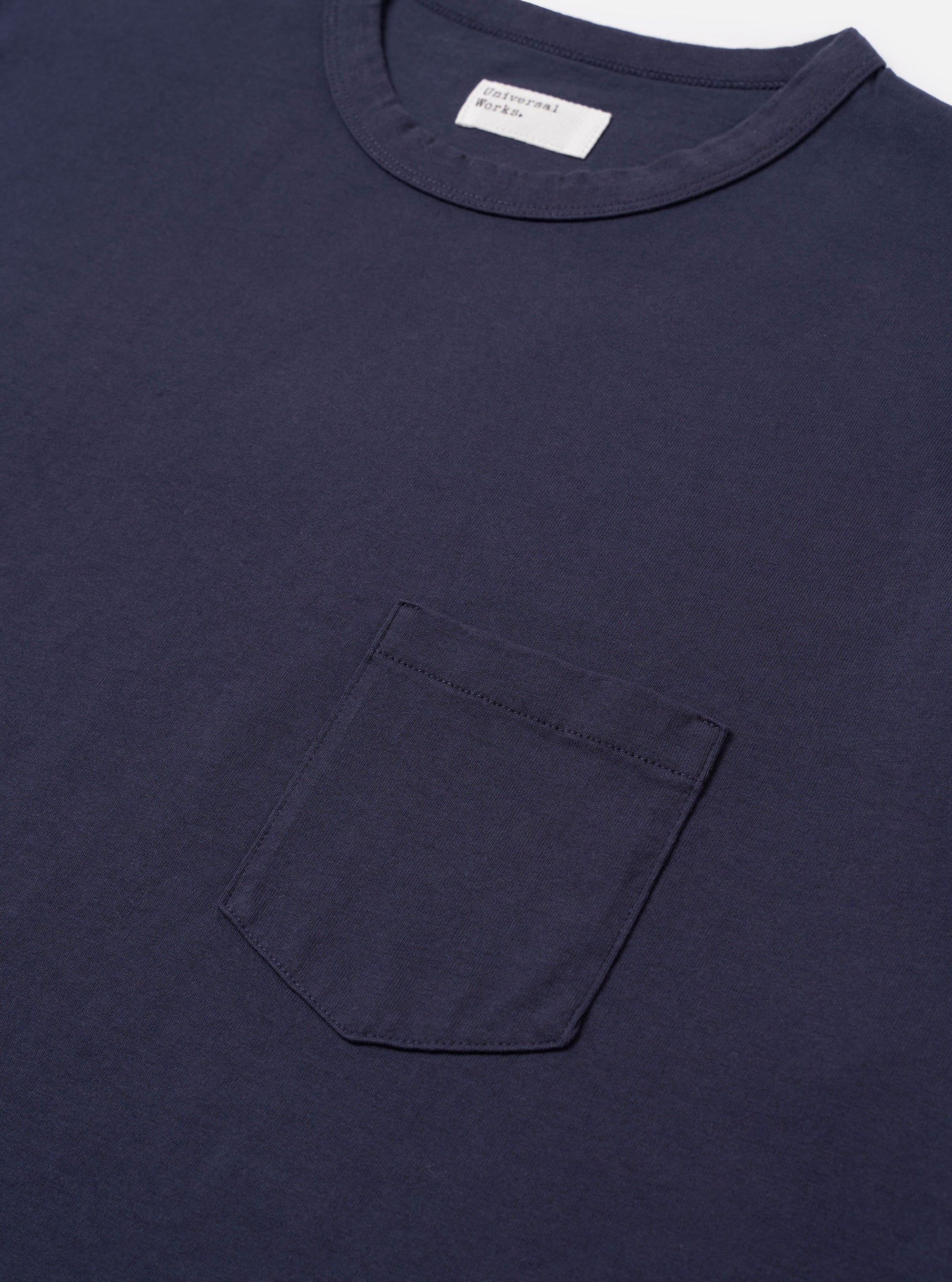 The Navy Recycled/Bio Jersey Core Pocket Tee is shown from a rear angle as a flat lay against a plain white background. The image highlights the clean, simple construction of the back panel, the ribbed crew neck, and the soft texture of the navy blue jersey fabric.