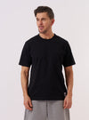 A model wears the Black Recycled/Bio Jersey Core Pocket Tee against a plain white background. The T-shirt features a classic crew neckline, short sleeves, and a single patch pocket on the left chest. The black jersey fabric has a smooth, matte finish. The model is shown from the chest up, highlighting the fit and the pocket detail.