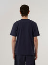 A model wears the Navy Recycled/Bio Jersey Core Pocket Tee, shown from a rear three-quarter angle against a plain white background. The T-shirt features a classic crew neck, short sleeves, and a straight hem. The deep navy blue jersey fabric has a soft, smooth appearance.