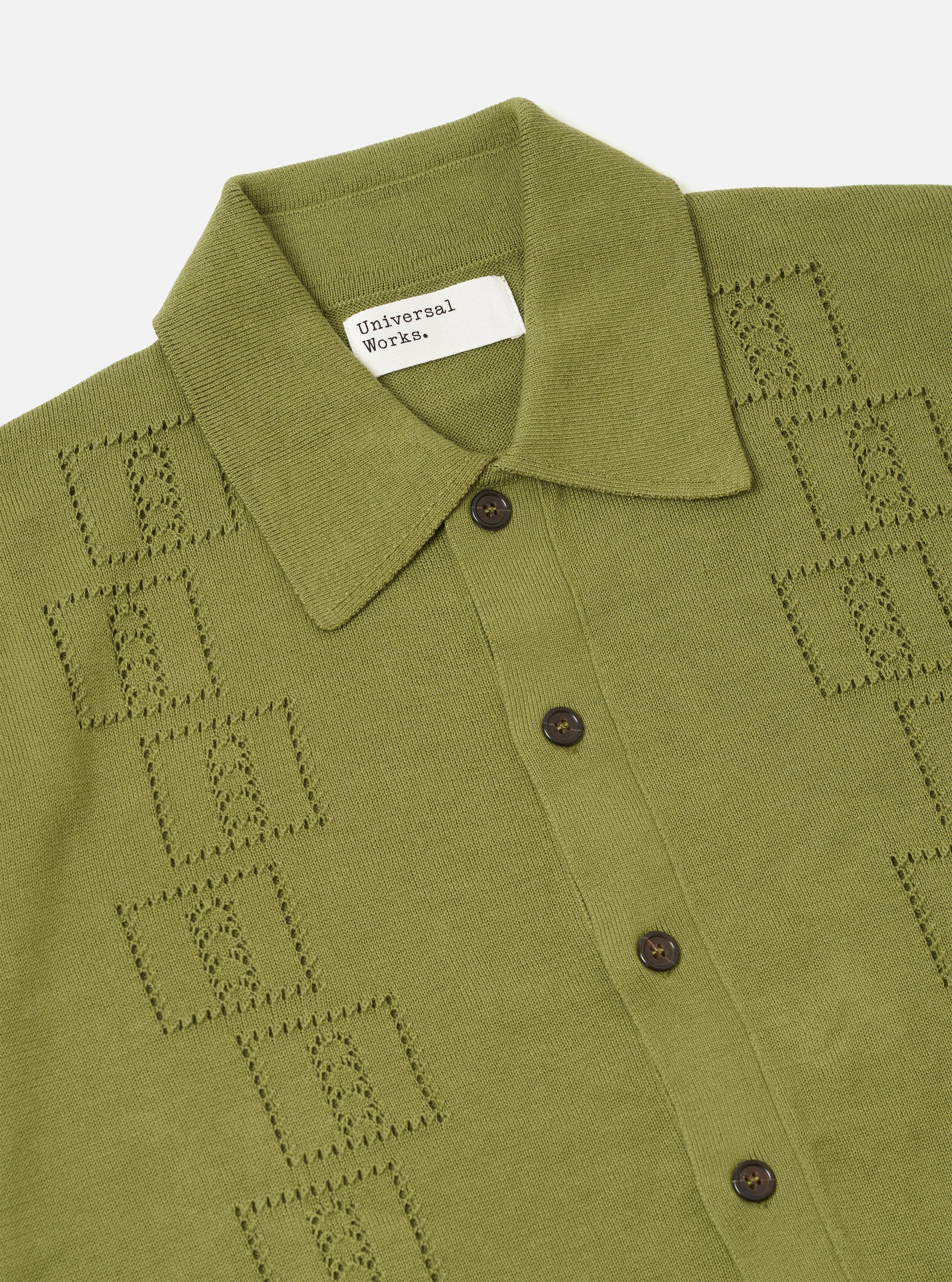 The Olive Cotton Lace Knit Jonny Knit Shirt is shown from the back as a flat lay against a plain white background. The image highlights the fine 12-gauge knit and the openwork square lace pattern of the 100% cotton fabric. The short sleeves and straight hem are clearly visible.