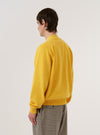 A model is wearing the Yellow Eco Cotton Knit Pocket David Cardigan, shown from a rear view against a plain white background. The cardigan features a relaxed fit, a straight hem with ribbed detailing, and long sleeves with ribbed cuffs. The yellow recycled cotton fabric has a soft, textured knit appearance.
