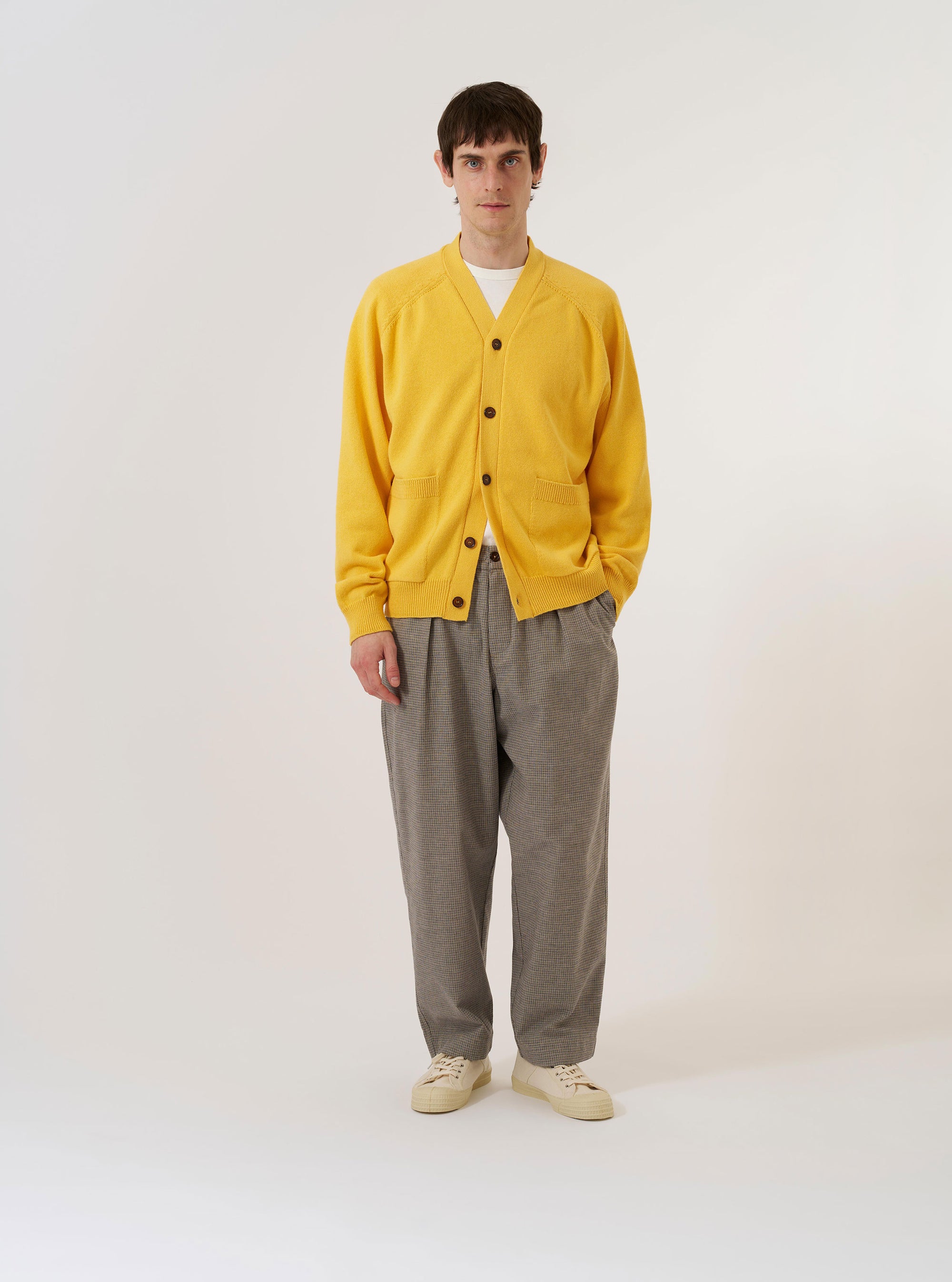 The Yellow Eco Cotton Knit Pocket David Cardigan is shown as a flat lay against a white background. The cardigan features a V-neckline, a five-button front closure, and two large patch pockets at the waist. The knit fabric has a textured, ribbed appearance in a vibrant yellow ochre color.