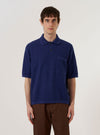 A model wears the Navy Fine Texture Tricot S/S Knit Polo against a plain white background. The polo features a three-button placket, a classic collar, and short sleeves with ribbed cuffs. The knit fabric has a visible fine-textured tricot pattern in a deep navy blue. The model is shown from the chest up, highlighting the garment's fit and texture.