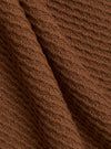 A close-up fabric swatch of the Brown Fine Texture Tricot S/S Knit Polo highlights the intricate raised rib pattern and soft texture of the brown cotton knit material. The fabric fills the frame, providing a detailed view of the garment's color and technical construction.