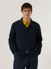 A model wears the Navy Eco Cotton Knit Jacket over a white t-shirt while standing against a plain white background. The jacket features a textured, chunky knit pattern, a classic button-up front with five buttons, and two lower patch pockets. The model is shown from the waist up in a front-facing studio shot.