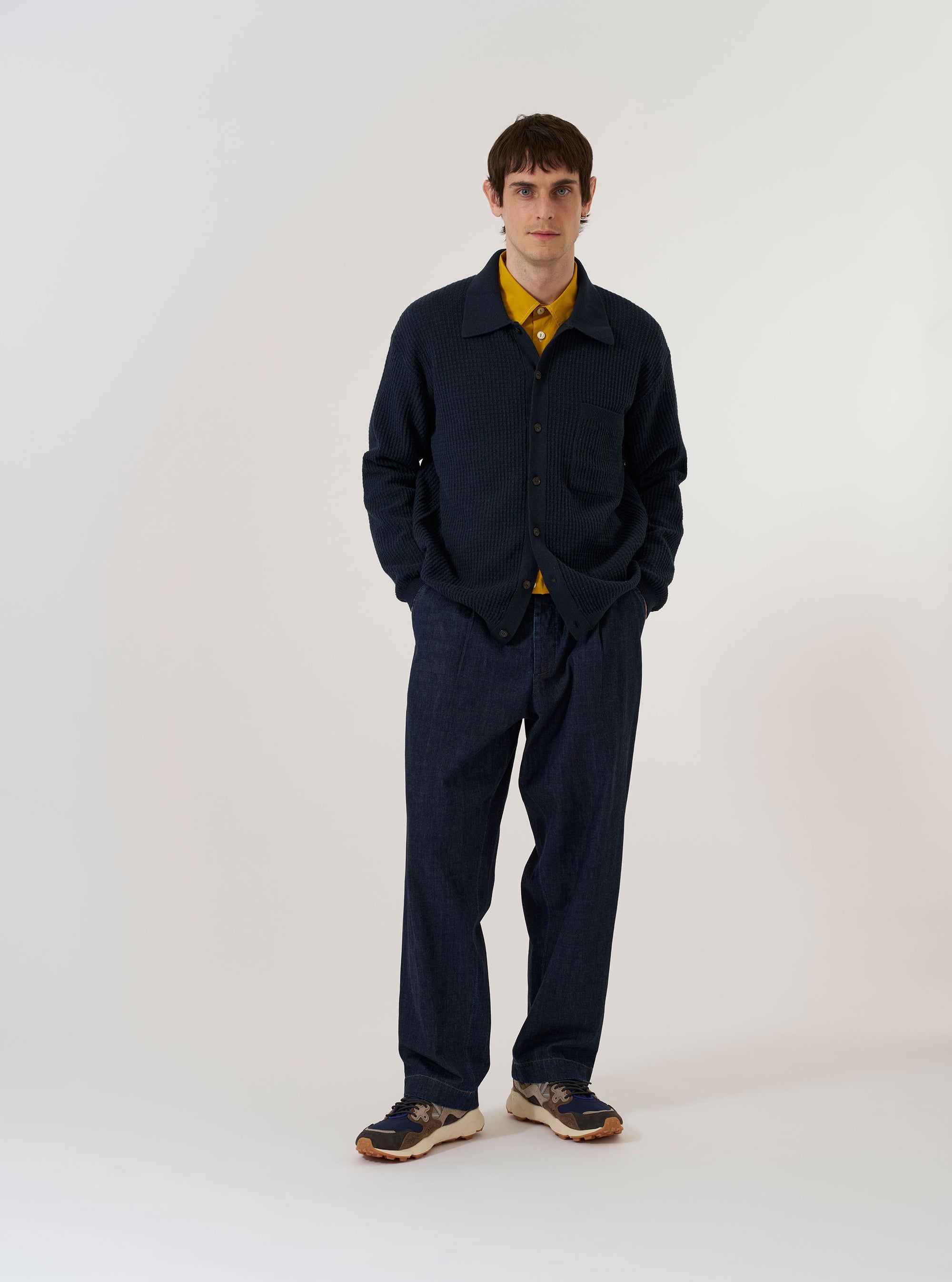 The Navy Eco Cotton Knit Jacket is presented as a flat lay against a solid white background. The jacket features a textured knit finish, a full-length five-button front closure, a classic collar, and two large patch pockets at the waist.