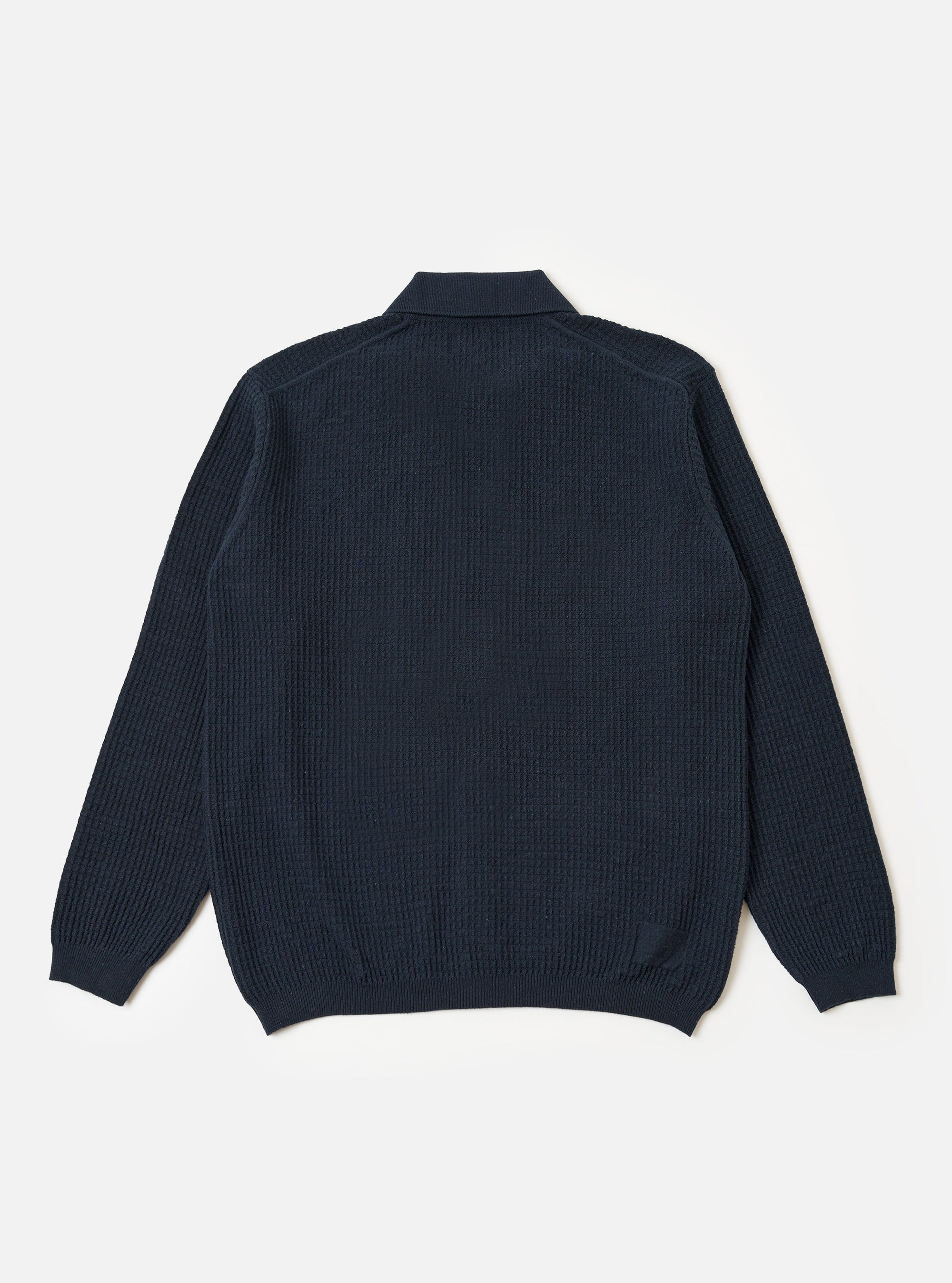 A model wears the Navy Eco Cotton Knit Jacket against a plain, light-colored background. The jacket features a textured knit construction, a five-button front closure, and two large patch pockets at the waist. The model is shown from the front, highlighting the garment's relaxed fit and ribbed detailing at the collar and cuffs.