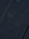 A close-up fabric swatch of the Navy Eco Cotton Knit Jacket highlights the detailed texture of the recycled cotton knit. The deep navy blue yarn is woven into a visible, structured pattern that creates a slightly raised surface.