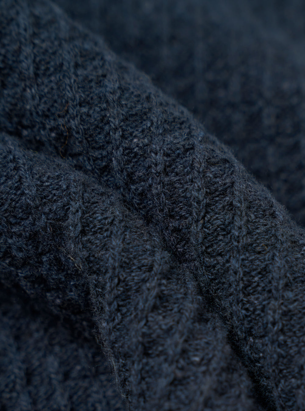 A close-up fabric swatch of the Navy Eco Cotton Knit Jacket shows the detailed texture of the dark blue knit material. The image focuses on the intricate weave and pattern of the recycled cotton threads. No model or mannequin is present.