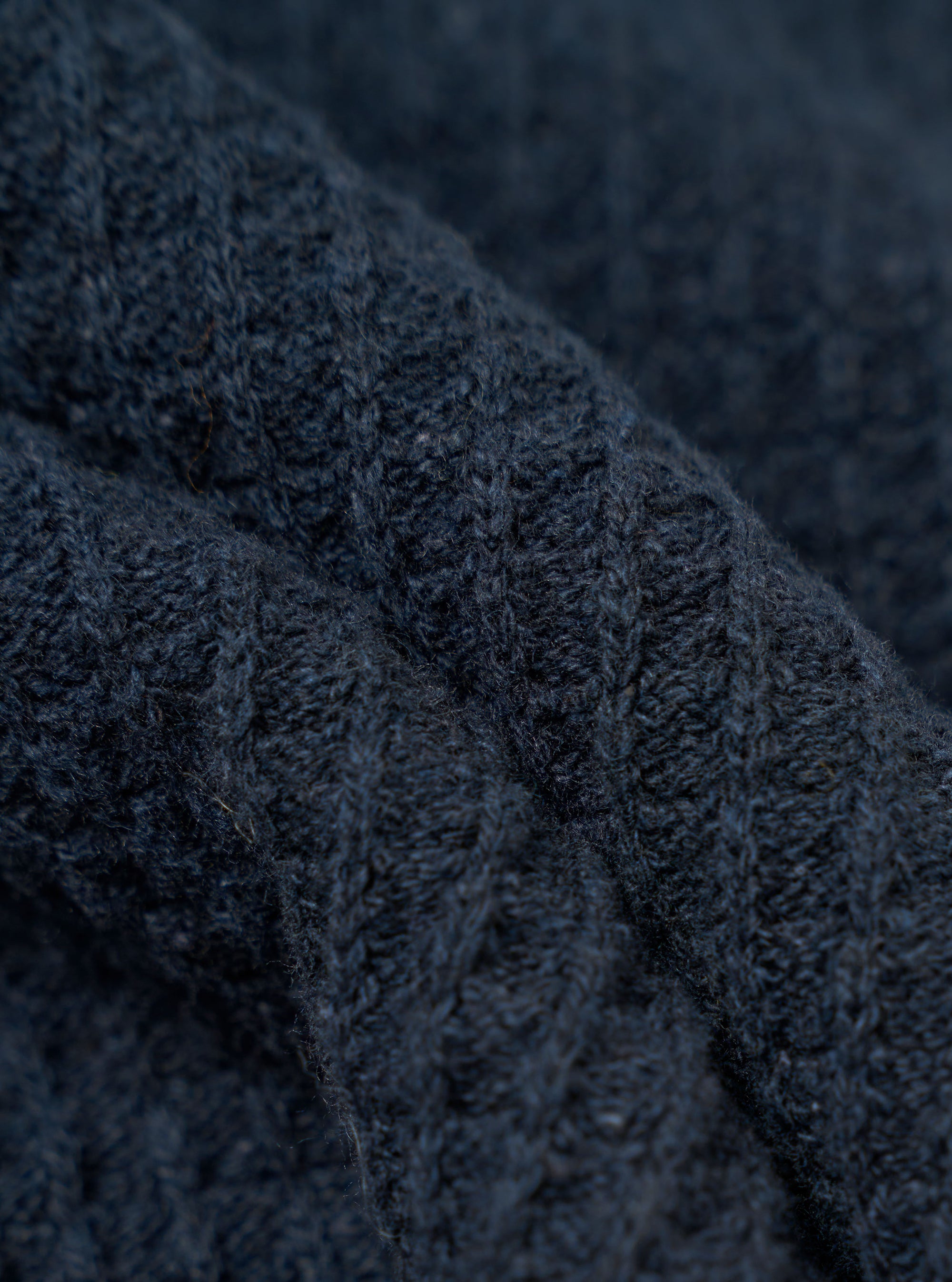 A close-up fabric swatch of the Navy Eco Cotton Knit Jacket shows the detailed texture of the dark blue knit material. The image focuses on the intricate weave and pattern of the recycled cotton threads. No model or mannequin is present.