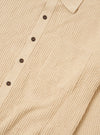 The Sand Eco Cotton Knit Jacket is shown from the back, worn by a model against a plain white background. The jacket features a clean, straight hem and a simple knit texture in a light sand color. The model is also wearing dark trousers, and the focus is on the fit and drape of the garment across the shoulders and back.