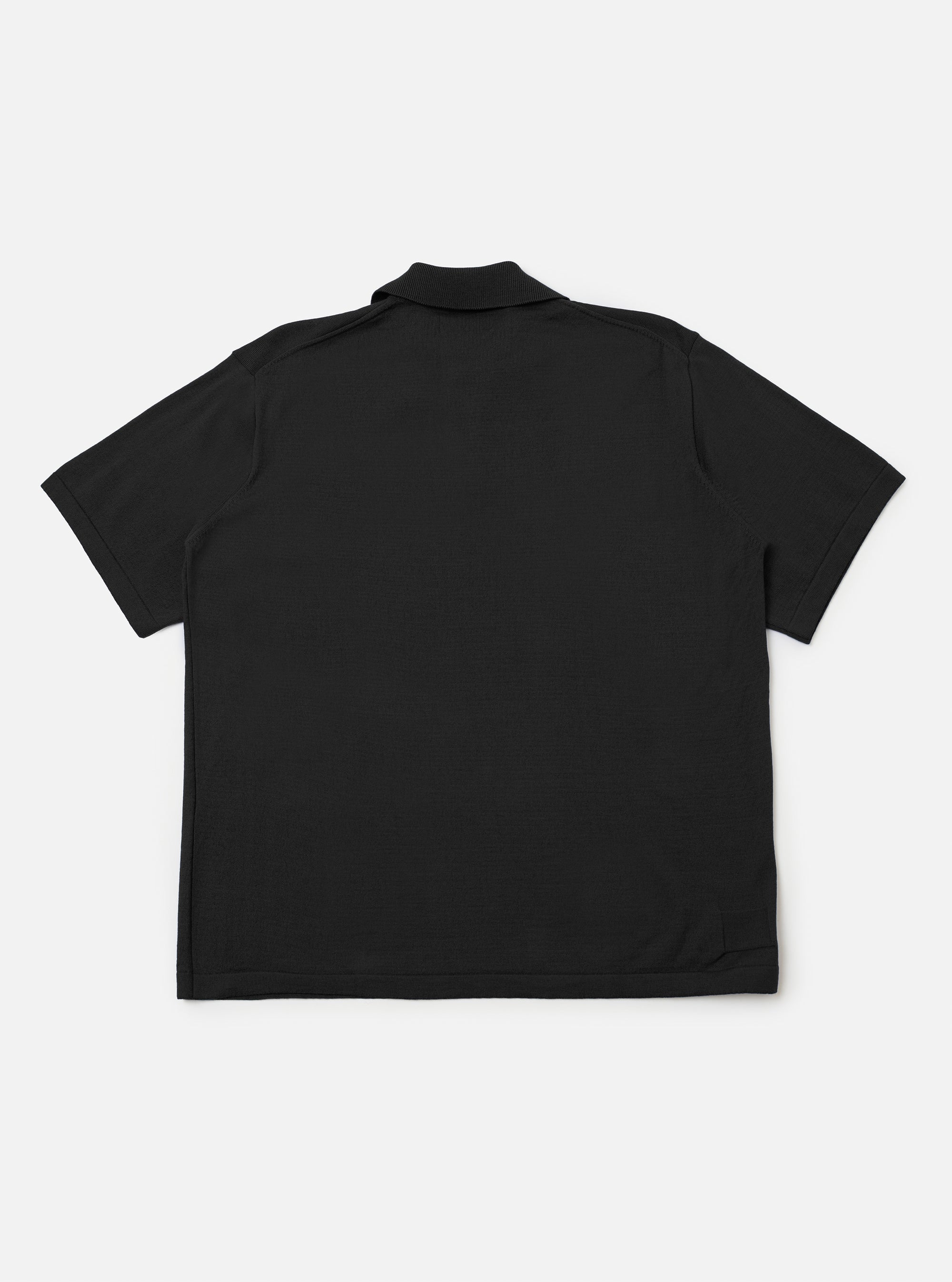 The Black Woolcot Bio S/S Pullover Knit Shirt II is shown from the back as a flat lay against a plain white background. The image highlights the clean, straight-cut back panel, short sleeves, and the smooth, fine-knit texture of the black merino and organic cotton blend fabric.