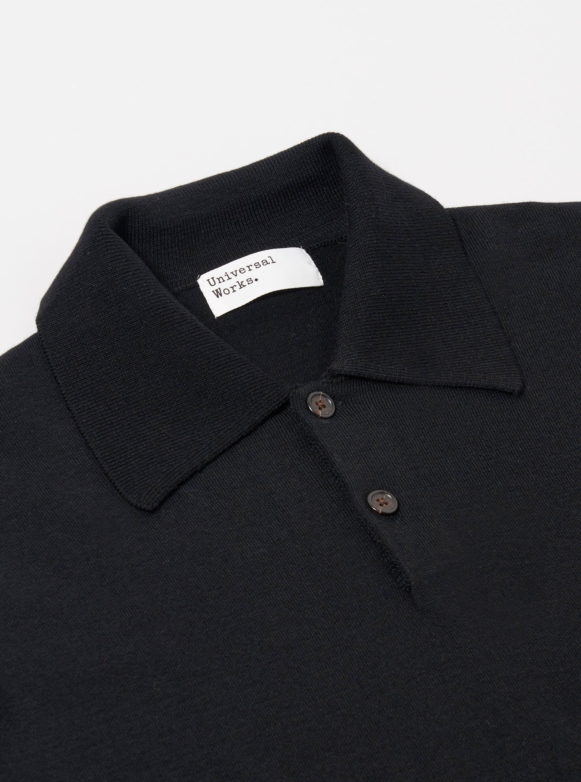 The Black Woolcot Bio S/S Pullover Knit Shirt II is shown from a rear angle as a flat lay against a plain white background. The image highlights the smooth, fine-gauge knit texture of the black fabric, the short sleeves, and the straight hem.