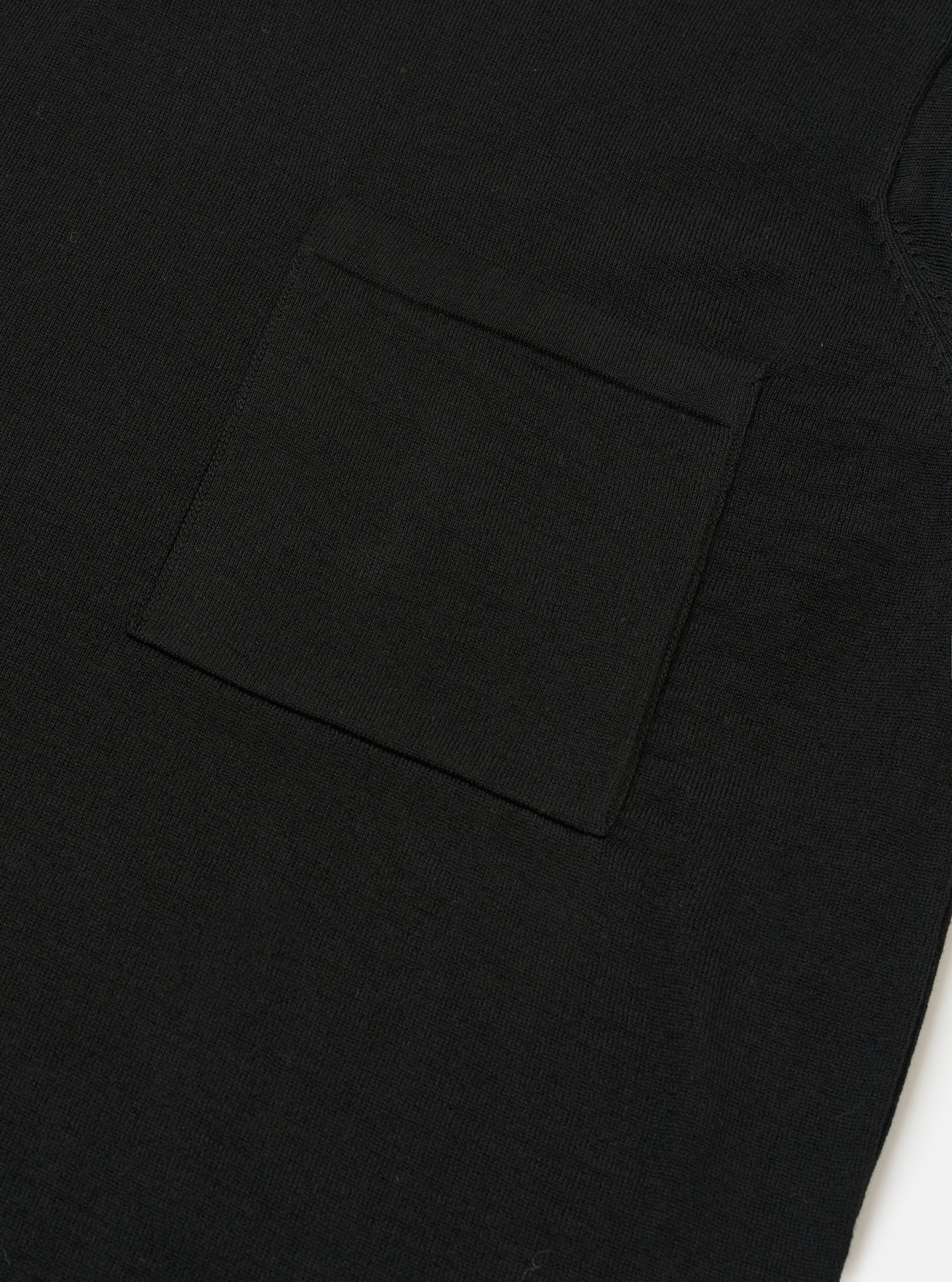 The Black Woolcot Bio S/S Pullover Knit Shirt II is shown from the back as a flat lay against a plain white background. The image highlights the shirt's boxy fit, short sleeves, and a large one-piece collar. The black knit fabric appears smooth and lightweight.