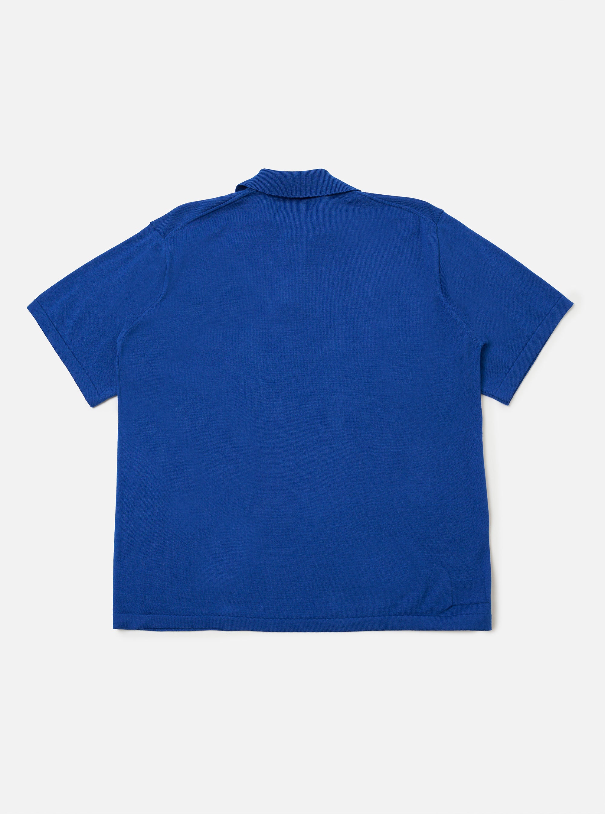 The Blue Woolcot Bio S/S Pullover Knit Shirt II is shown from the back as a flat lay against a plain white background. The knit shirt features short sleeves with ribbed cuffs and a matching ribbed hem. The blue fabric, a blend of merino and organic cotton, has a fine, soft texture.