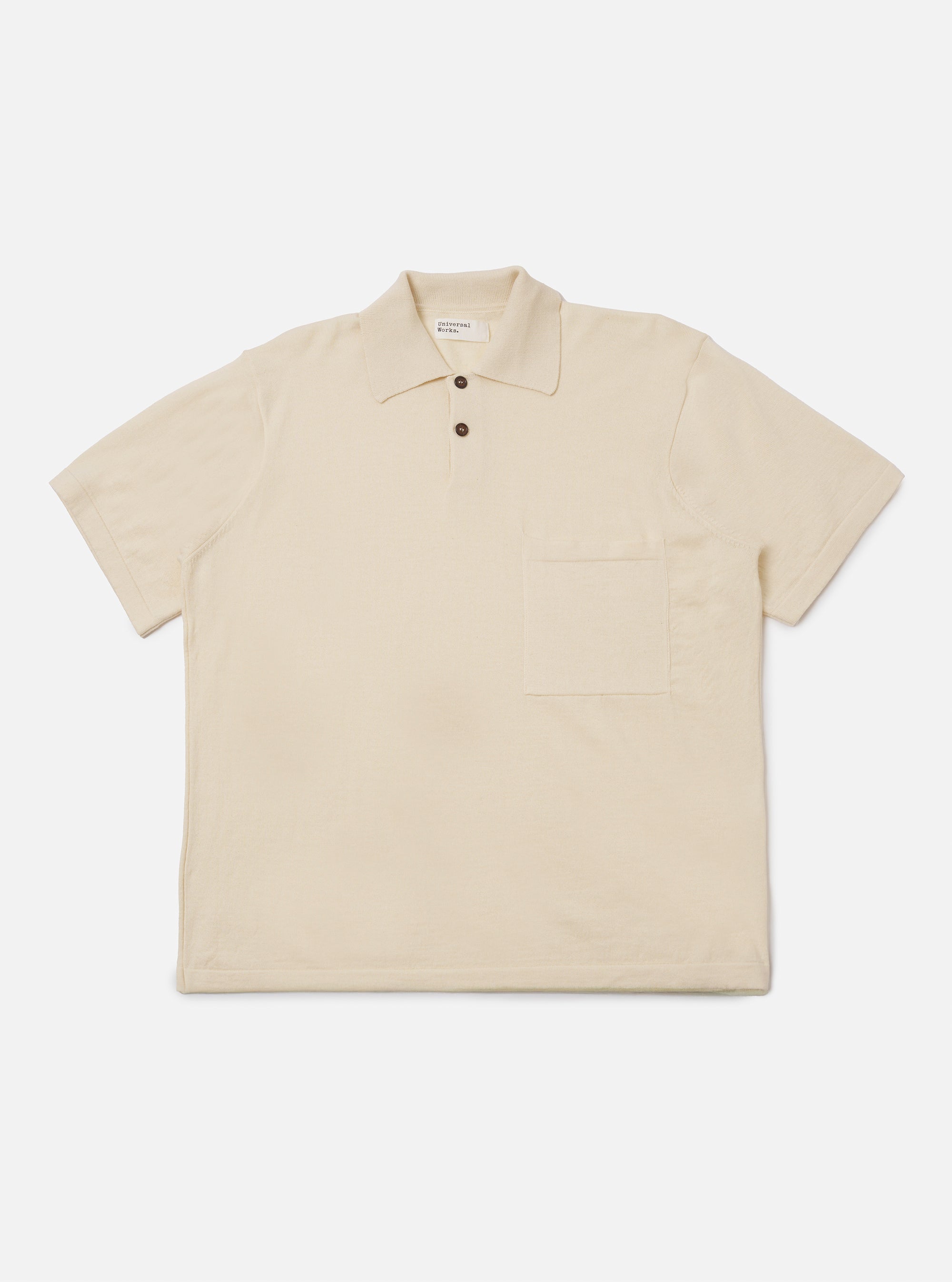 The Ecru Woolcot Bio S/S Pullover Knit Shirt II is shown as a flat lay against a plain white background. This short-sleeved knit shirt features a classic collar, a button placket with two buttons, and a single patch pocket on the left chest. The garment has a boxy fit and is made from a smooth, lightweight ecru-colored knit fabric.