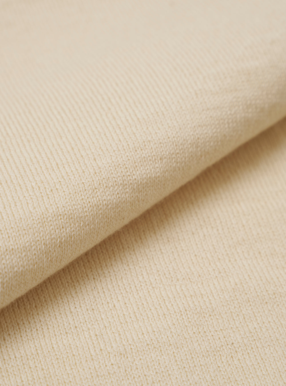 A close-up swatch image of the Ecru Woolcot Bio S/S Pullover Knit Shirt II highlights the fabric's soft, off-white color and smooth, lightweight knit texture. The image focuses on the fine blend of merino wool and organic cotton.