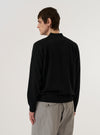 A model wears the Black Woolcot Bio Loose Cardigan II, shown from the back against a plain white background. The cardigan features a relaxed, loose fit with dropped shoulders and ribbed detailing at the cuffs and hem. The garment is constructed from a soft black knit fabric.
