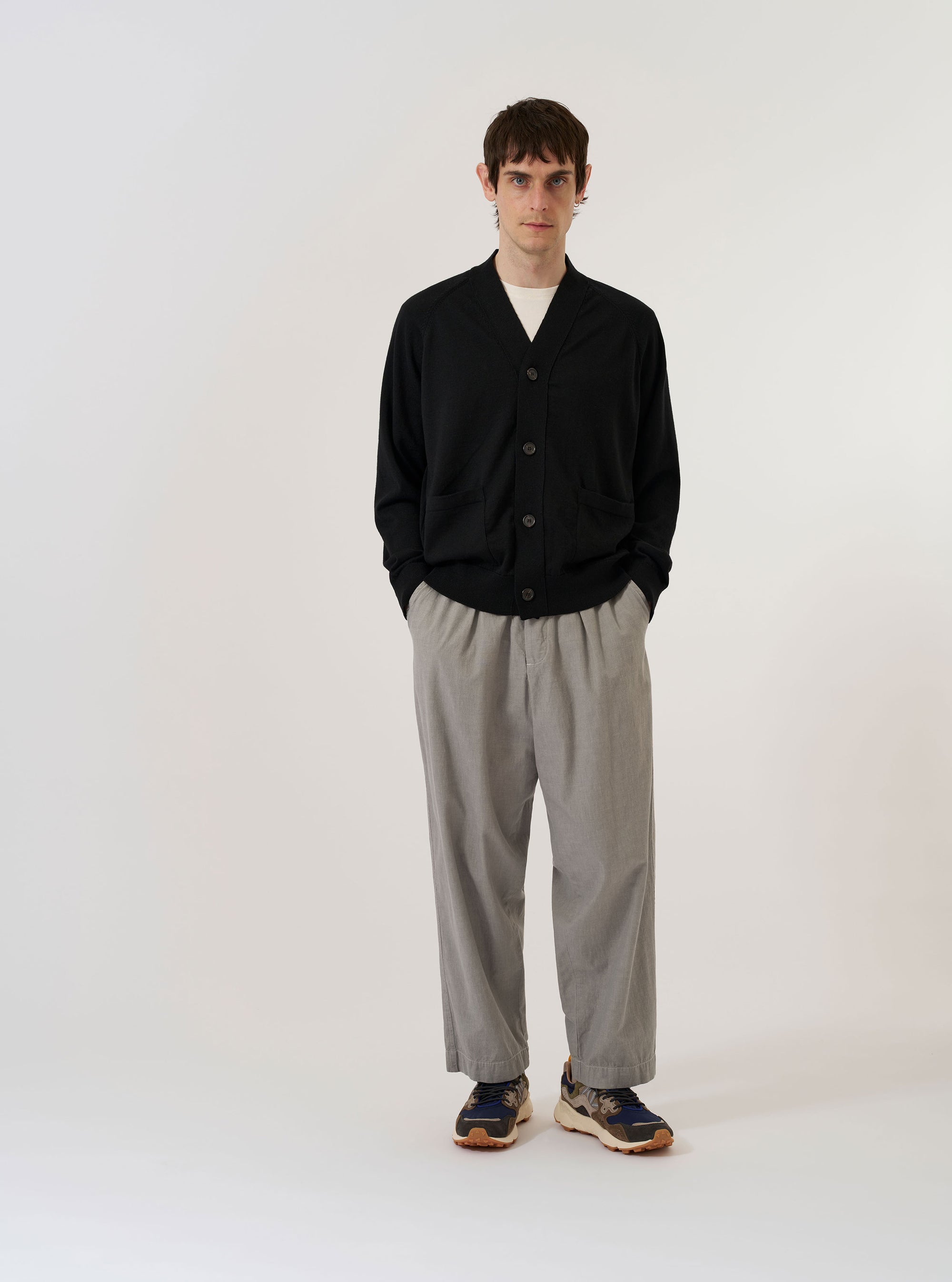 The Black Woolcot Bio Loose Cardigan II is displayed as a flat lay against a plain white background. The cardigan features a V-neckline, a central button-down closure, and two large patch pockets at the waist. The black knit material shows a soft texture with ribbed detailing on the cuffs and hem.