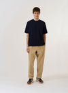 The Navy Merino Fine Knit Knit Tee is shown as a flat lay against a plain white background. The garment is a short-sleeved crewneck t-shirt made from a fine navy blue merino wool knit. It features a ribbed collar, cuffs, and hem, highlighting its clean and classic construction.
